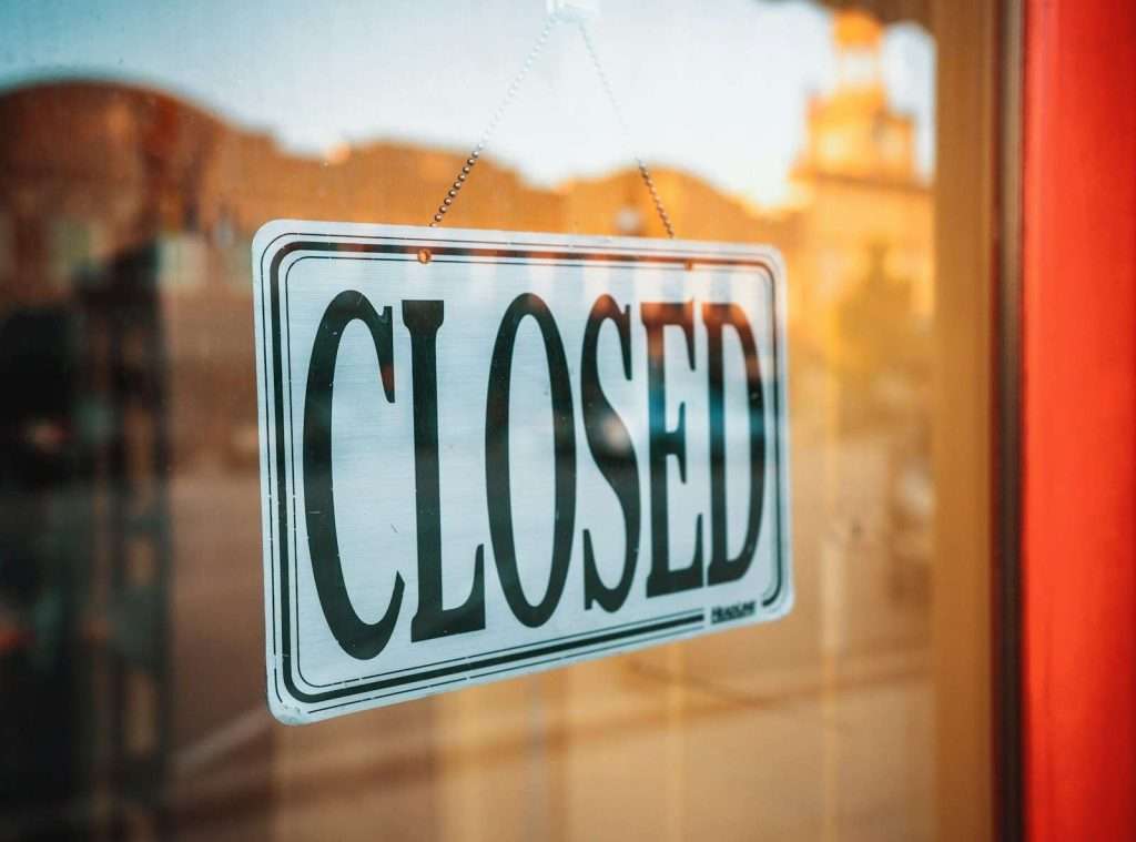 A "Closed" sign hangs on a glass door, indicating the business is not currently open, much like the feeling of anticipation when a HUD housing waiting list opens.