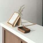 A minimalist desk features a wooden organizer, small plant, document holder, and tray with keys on a white surface, creating a calm workspace ideal for a Section 8 landlord managing HUD housing documents.