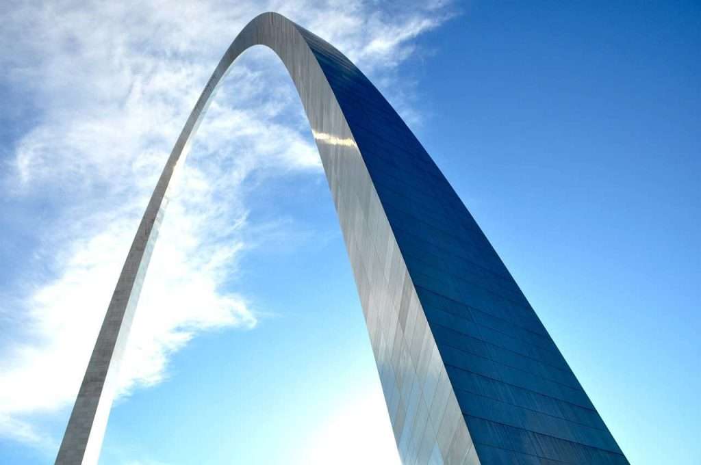 The Gateway Arch in St. Louis stands tall against a clear blue sky with a few clouds, symbolizing dreams reaching new heights. Nearby, opportunities like HUD housing and Section 8 applications in Missouri provide foundations for families aspiring to their own bright futures.