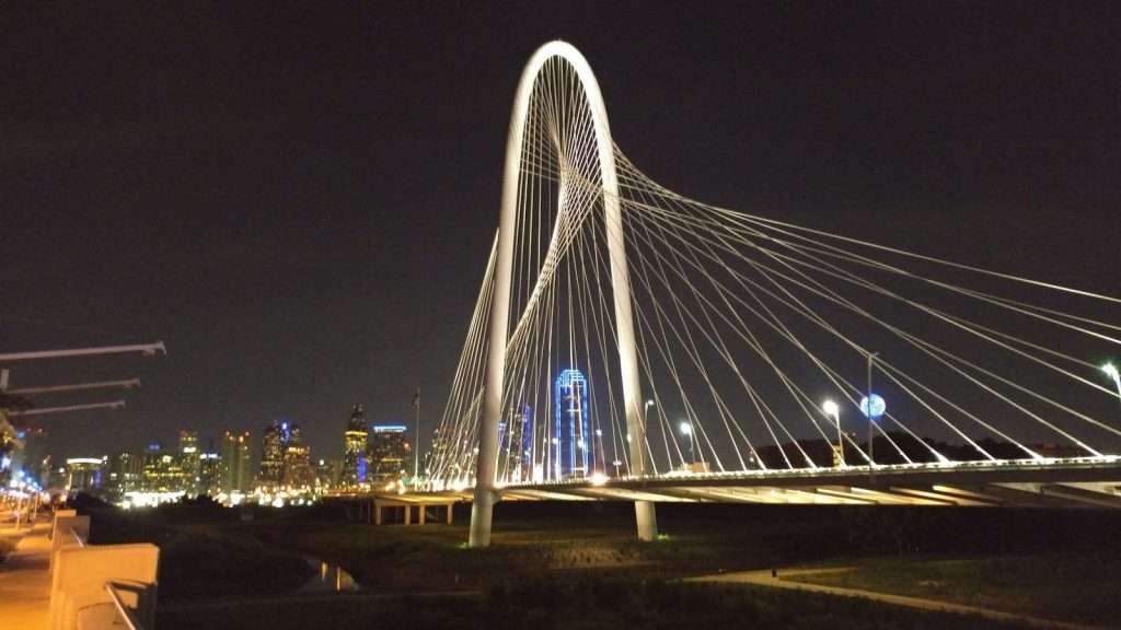 The illuminated cable-stayed bridge at night, juxtaposed against the city skyline, stands as a symbol of progress akin to Texas HUD housing initiatives transforming urban landscapes.