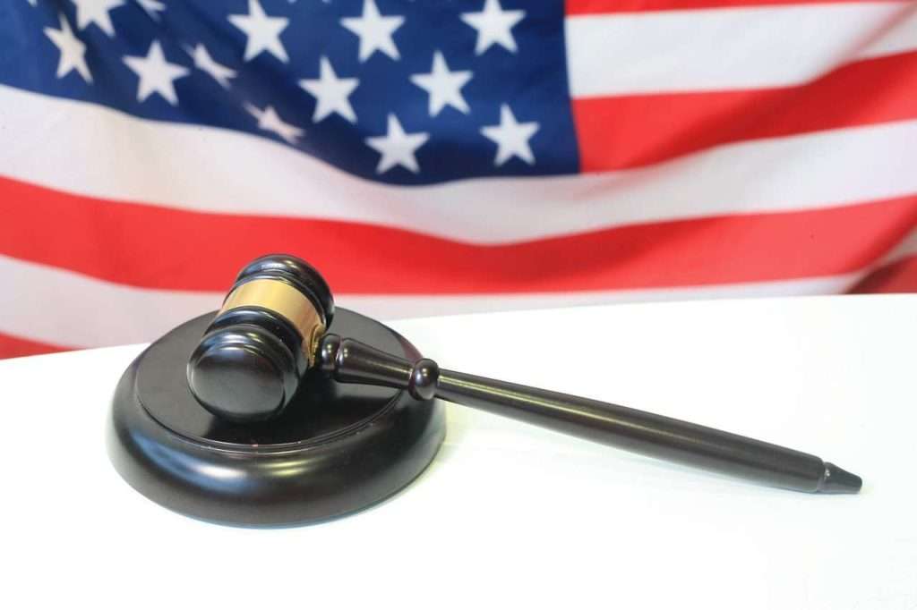 A judge's gavel rests on a sounding block with an American flag in the background, symbolizing justice at the heart of a Section 8 lawsuit.